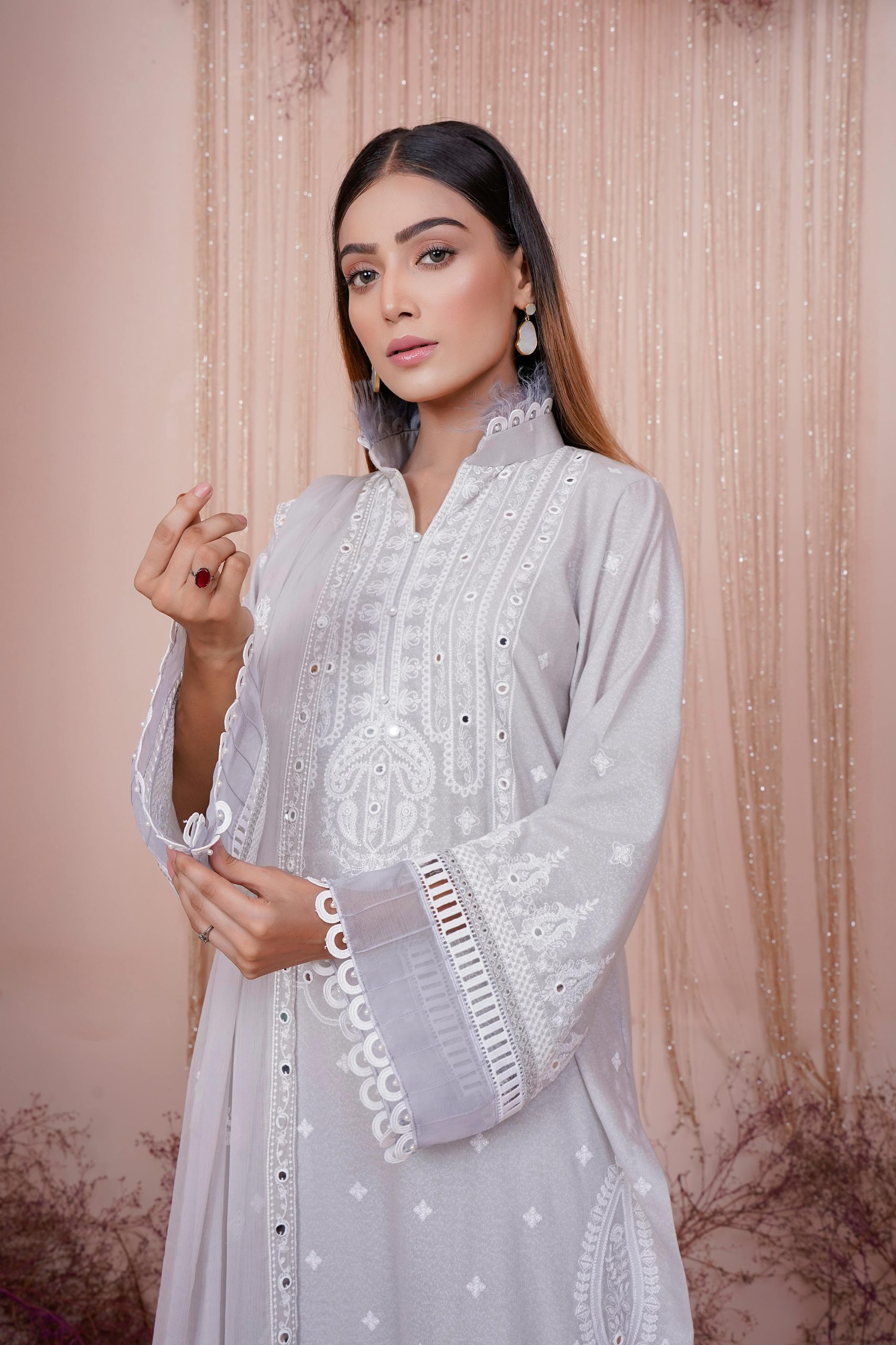Portrait of a young woman in an elegant embroidered dress with intricate details.